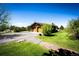 Exterior view of the home featuring a long driveway and lush green landscaping at 2965 Wagner St, Strasburg, CO 80136