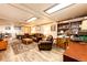 Spacious basement living room with a leather furniture set, wood-style flooring, and ample natural light and shelving space at 2965 Wagner St, Strasburg, CO 80136