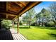 Covered porch with wooden flooring and a swing overlooks the expansive lawn and trees at 2965 Wagner St, Strasburg, CO 80136