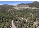 An aerial view reveals a home set in a vast, wooded area with winding roads and mountain views at 8722 S Ault Ln, Morrison, CO 80465