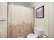 Bathroom with a toilet and shower featuring a patterned curtain and framed artwork at 8722 S Ault Ln, Morrison, CO 80465