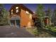 Charming two-story home showcasing a stone facade garage, wood siding, and mature trees at 8722 S Ault Ln, Morrison, CO 80465