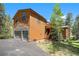 Charming exterior with wood siding, stone accents, and a two-car garage in a serene forest setting at 8722 S Ault Ln, Morrison, CO 80465
