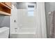 White tiled bath and shower combination with a shower curtain, cabinet, and window at 2011 S Vallejo St, Denver, CO 80223