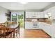 Bright kitchen and dining area featuring white cabinetry, hardwood floors, and access to the backyard at 2011 S Vallejo St, Denver, CO 80223