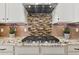 Close-up of the gourmet kitchen featuring a gas range, custom backsplash, and granite countertops at 15720 Columbus Mountain Dr, Broomfield, CO 80023