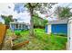 Spacious backyard featuring a blue house with a sunroom, lush green lawn, mature trees, and a matching storage shed at 1720 Trenton St, Denver, CO 80220