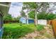 Large backyard with a blue storage shed, garden beds, mature trees, and a well-maintained lawn at 1720 Trenton St, Denver, CO 80220