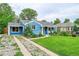 Inviting blue bungalow with mature trees, a green lawn, and a quaint front porch at 1720 Trenton St, Denver, CO 80220