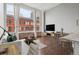 Bright, open living space featuring exposed brick, tall windows with city views, and hardwood floors at 720 16Th St # 306, Denver, CO 80202