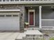 Welcoming front porch with stone accents, gray siding, and a red front door, leading to a two-car garage at 1373 E Witherspoon Dr, Elizabeth, CO 80107