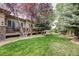 A backyard view shows a patio overlooking a spacious lawn with beautiful trees and landscaping at 6783 E Orchard Rd, Greenwood Village, CO 80111