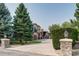 View of the house's exterior with mature landscaping and a stone pillar entrance at 6783 E Orchard Rd, Greenwood Village, CO 80111