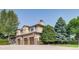 Exterior view of a stucco home featuring multiple garage doors and mature landscaping at 6783 E Orchard Rd, Greenwood Village, CO 80111
