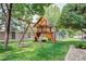 A wooden playset features swings, a slide, climbing wall, and lookout tower on the lush lawn at 6783 E Orchard Rd, Greenwood Village, CO 80111