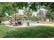 An outdoor pool area features a slide, lounge chairs, patio umbrellas, hot tub, and lush greenery at 6783 E Orchard Rd, Greenwood Village, CO 80111