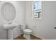 Compact half bath featuring a pedestal sink, toilet, and a bright window at 1242 Penner Dr, Erie, CO 80026