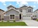 Beautiful two-story home with stone accents, gray siding, well-manicured lawn, and attached two car garage at 6263 E 142Nd Pl, Thornton, CO 80602