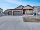 Charming two-story home with a three-car garage and stone accents on the front porch, set against a blue sky at 4877 Cattle Cross Rd, Castle Rock, CO 80104