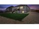 Night falls on the backyard with lush grass and gravel surrounding the home, enclosed by a wooden fence at 8020 E 136Th Dr, Thornton, CO 80602