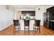 Modern kitchen with stainless steel appliances, dark cabinets, and a large island with bar seating at 8020 E 136Th Dr, Thornton, CO 80602