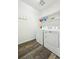 A bright laundry room boasts wooden floors, white walls, open shelving, and modern washer and dryer machines at 8020 E 136Th Dr, Thornton, CO 80602