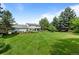 Spacious backyard with lush lawn, mature trees, patio, and view of the home's exterior at 5698 Green Oaks Dr, Greenwood Village, CO 80121