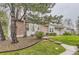 Inviting exterior view of a home with mature trees, green lawn, and partial brick facade at 5404 W Canyon Trl # C, Littleton, CO 80128