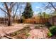 Picturesque backyard with stone pathway, lush garden beds, mature trees, and privacy fencing at 1578 S Syracuse St, Denver, CO 80231