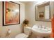 A half bathroom with toilet, sink, mirror, and vintage art at 1578 S Syracuse St, Denver, CO 80231