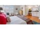 Bedroom featuring wood floors, a bed with colorful pillows, shuttered windows, and adjacent bathroom at 1578 S Syracuse St, Denver, CO 80231