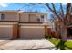 Two-story townhouse showcasing a tan exterior, brick accents, a concrete driveway, and an attached one-car garage at 1578 S Syracuse St, Denver, CO 80231