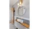 Bathroom featuring a modern vanity sink, round mirror, and gray wainscoting at 4040 Ames St, Wheat Ridge, CO 80212