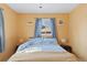 Bright bedroom with a blue and white comforter, yellow walls, and a window with blue curtains at 4040 Ames St, Wheat Ridge, CO 80212