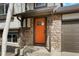 Inviting front entrance with an orange door, stone accents, and a covered porch, creating a welcoming curb appeal at 12050 Dahlia Dr, Thornton, CO 80241