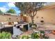 Outdoor living space featuring a seating area, grill, and mature tree surrounded by potted plants and flowers at 11241 E Cimmarron Dr, Englewood, CO 80111