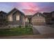 Exterior view of a home featuring stone accents, a manicured lawn, and a two-car garage under a vibrant sunset at 4536 Shady Path Ln, Castle Rock, CO 80104