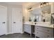 Modern bathroom featuring double sinks, gray cabinetry, and stylish lighting fixtures over black tile floors at 6550 S Oak Ct, Littleton, CO 80127