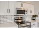Modern kitchen with stainless steel appliances, white cabinets, and subway tile backsplash at 6550 S Oak Ct, Littleton, CO 80127
