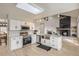 Open kitchen featuring a skylight, white cabinets, stainless appliances, and a view of the living room fireplace at 6550 S Oak Ct, Littleton, CO 80127