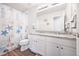 Bright bathroom featuring white cabinets, granite countertops, a vanity with double sinks, and nautical decor at 5354 Blue Lunar Ln, Castle Rock, CO 80104