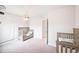 Neutrally decorated bedroom with carpet, a wood crib, a themed world map, and a wood accent chandelier at 5354 Blue Lunar Ln, Castle Rock, CO 80104
