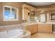 Bright bathroom featuring a bathtub near a window, dual sinks, and travertine floors at 913 Alkire Ct, Golden, CO 80401