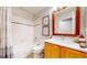 Well-lit bathroom with tiled tub, stylish vanity, and warm wood-framed mirror at 1229 Berganot Trl, Castle Pines, CO 80108