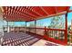 Wooden deck with red railing, pergola, and views of the surrounding greenery at 1229 Berganot Trl, Castle Pines, CO 80108