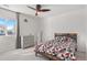 Bright bedroom featuring a bed with geometric patterned bedding, ceiling fan, and window with neighborhood views at 11885 Helena St, Commerce City, CO 80022
