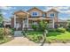 Charming two-story home featuring a welcoming porch, brick accents, manicured lawn, and beautiful landscaping at 942 Xenon Ct, Golden, CO 80401