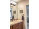 Bathroom featuring double sinks with wood cabinetry, light fixtures, and a large mirror at 6588 S Sheridan Loop, Littleton, CO 80123