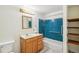 A full bathroom with a toilet, sink, vanity, wood cabinets, blue tiles, and wood shelving at 2043 E Nichols Dr, Centennial, CO 80122