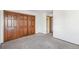 A carpeted bedroom featuring a closet with wood doors, and a view into the bathroom at 2043 E Nichols Dr, Centennial, CO 80122
